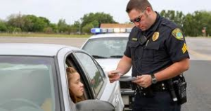 Law Office of Kevin Bessant A police officer stood outside a car window, meticulously checking the driver’s documents for any discrepancies that could result in a traffic ticket.