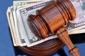 Bond Hearing Attorney A wooden gavel rests on top of US dollar bills placed on a dark blue surface, evoking the intensity of a bond hearing.